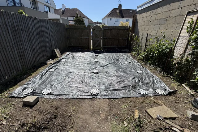 Ground screw heads visible through a black ground membrane during site progress.